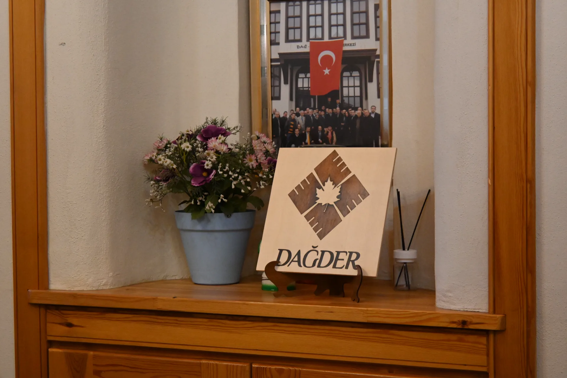 Pencere önünde DAĞDER logosu ve çiçekler